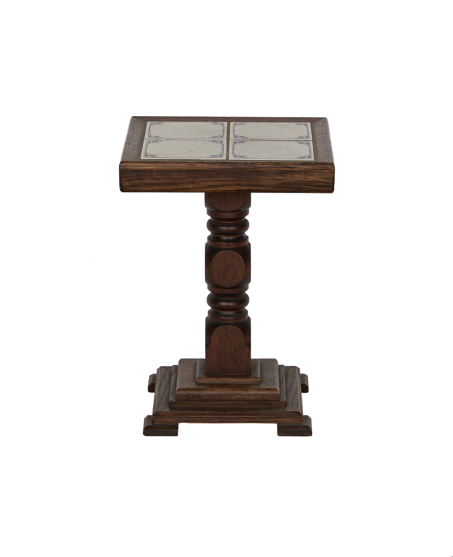 Close-up of vintage French oak side table with ornate Delft tile top.