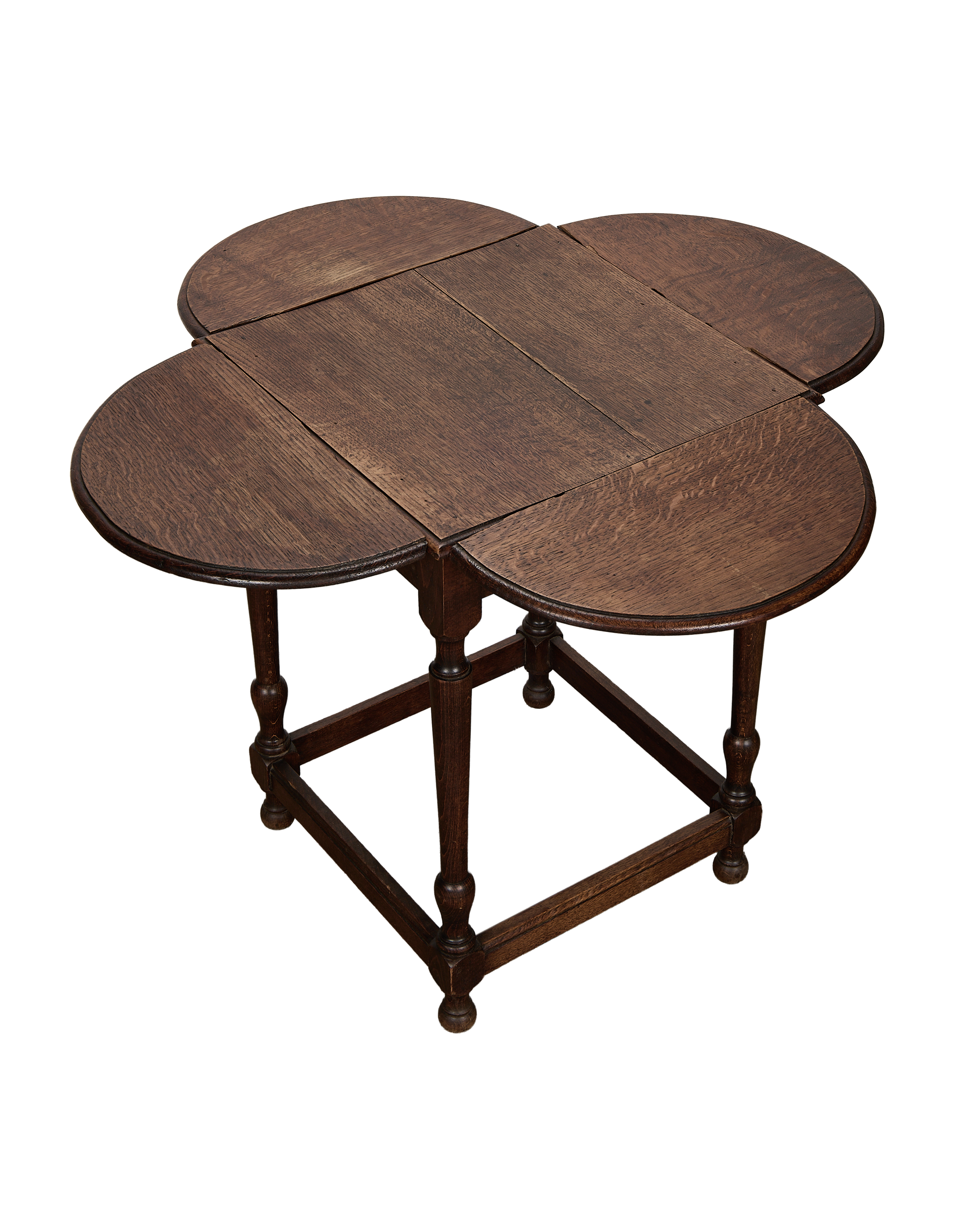 Vintage French oak clover drop-leaf table, leaves extended, showing rich wood grain.