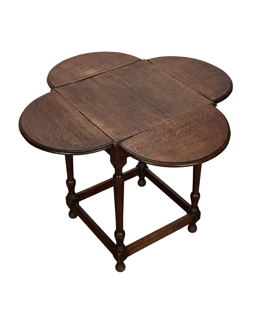 Vintage French oak clover drop-leaf table, leaves extended, showing rich wood grain.