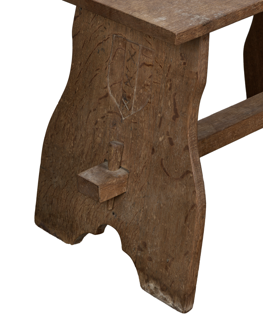 Vintage French oak church stool, close-up of side leg with carved shield detail.