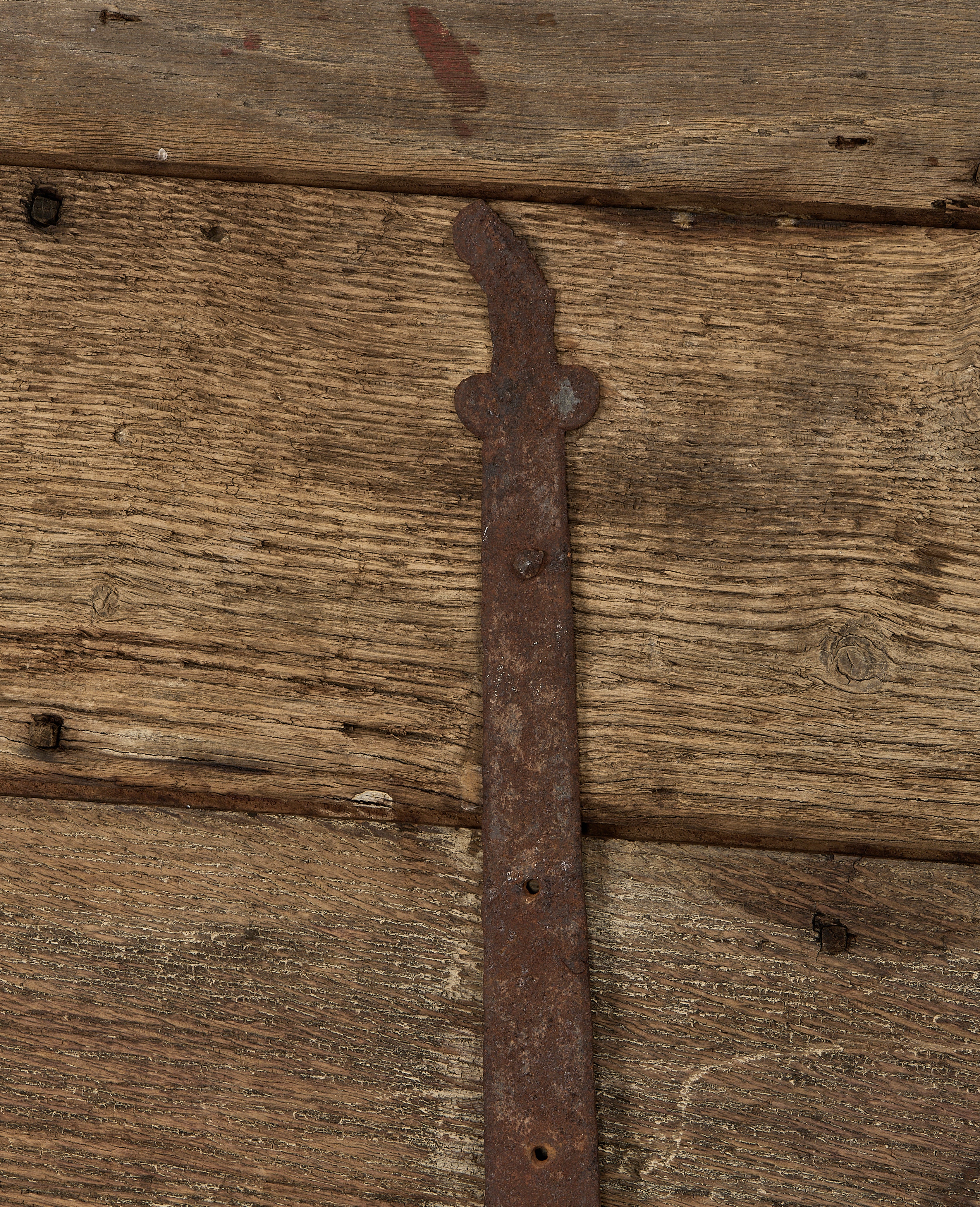 Detail of rustic forged iron hinge and weathered vintage French oak chest planks.