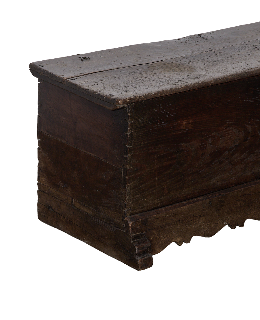 Vintage French oak chest, showing worn dark wood, dovetailed corner, and carved bottom edge.