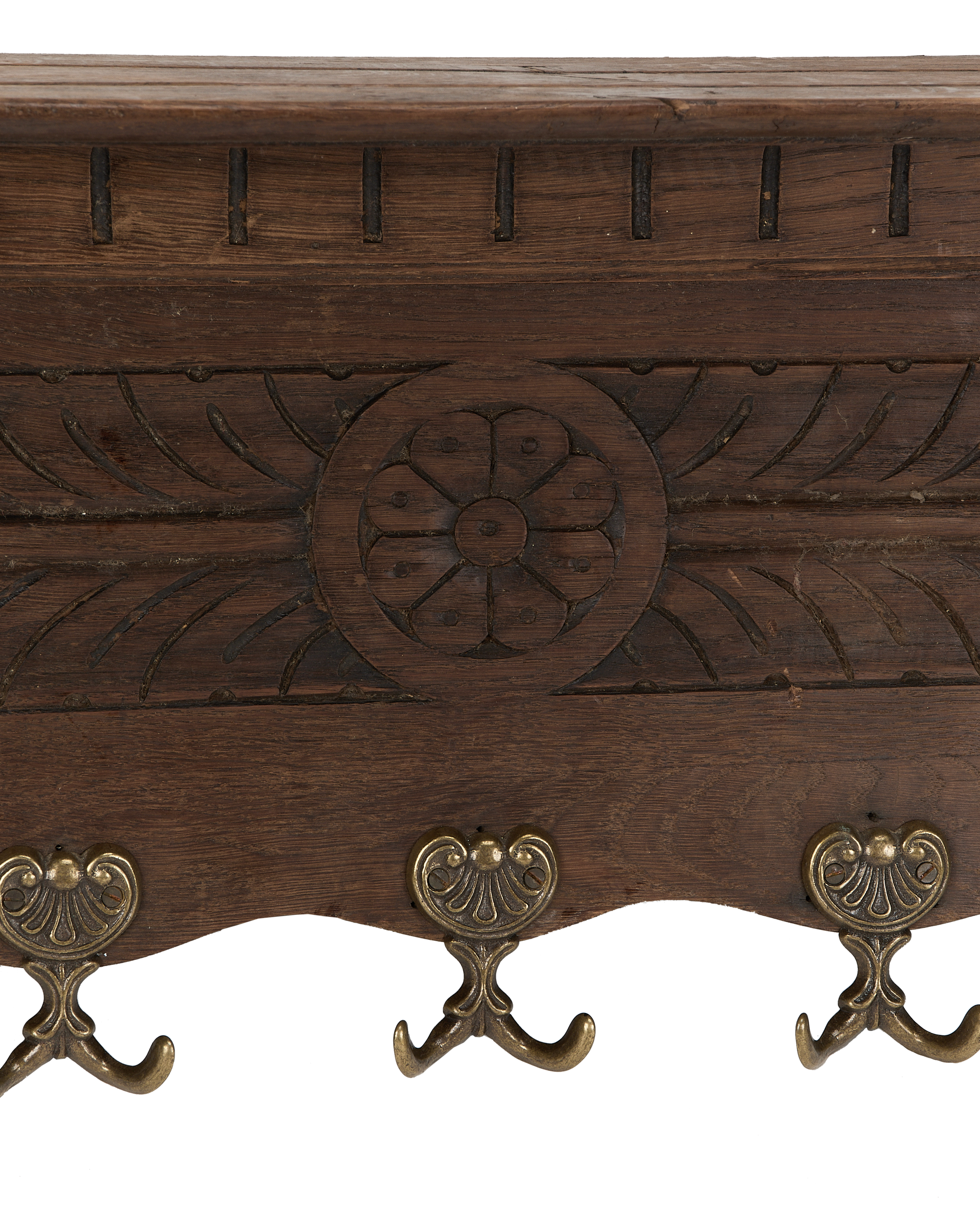 Close-up of vintage French oak hanging shelf, showing elaborate brass hooks and carved floral details.