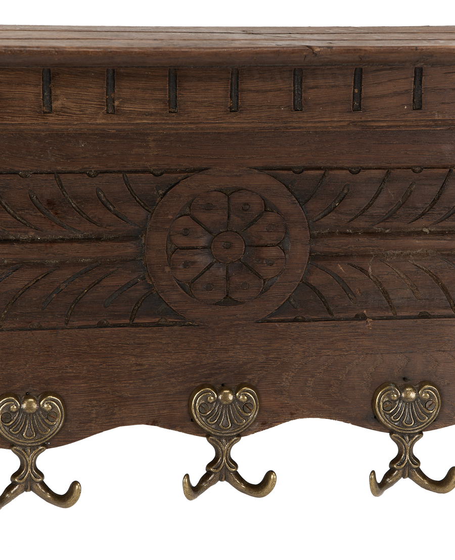 Close-up of vintage French oak hanging shelf, showing elaborate brass hooks and carved floral details.