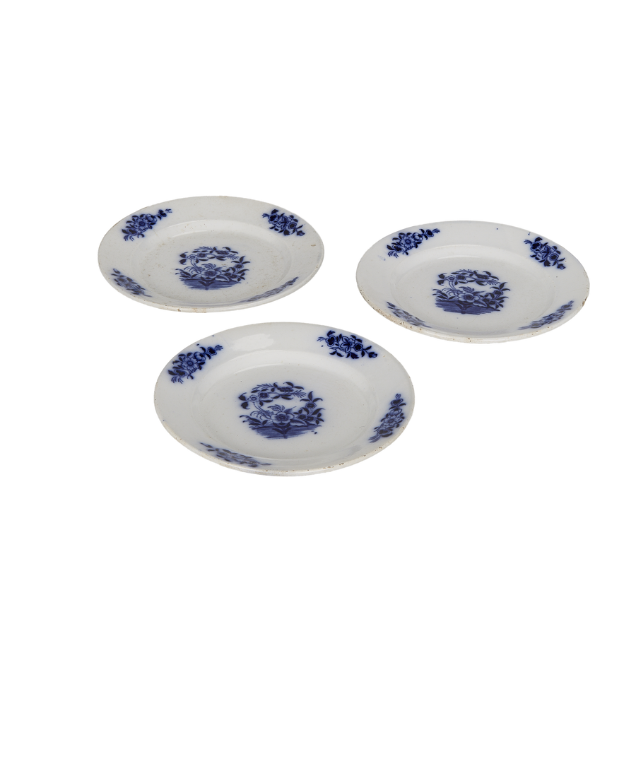 Three vintage French blue and white plates, showing detailed floral patterns and rustic charm.