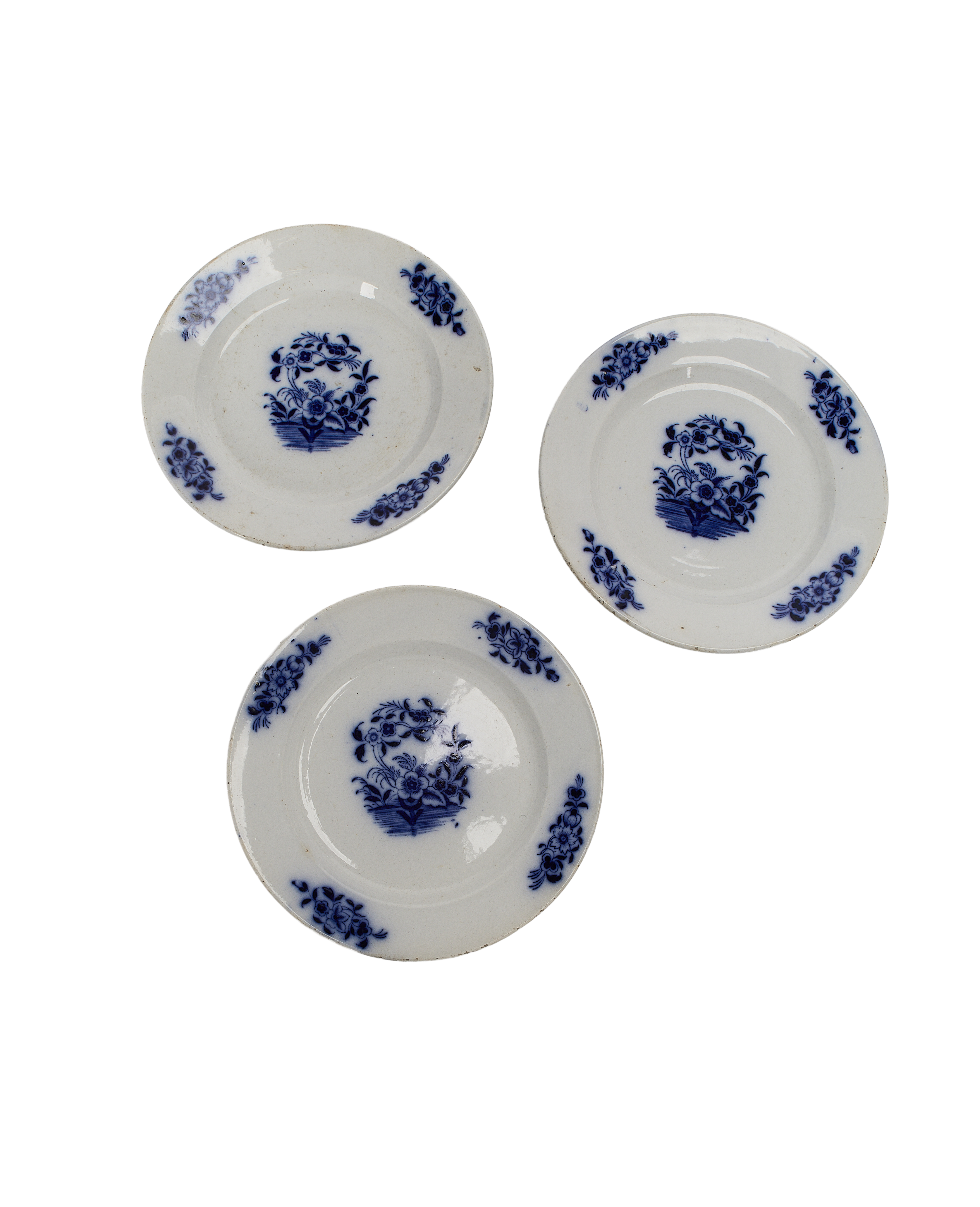 Three vintage French blue and white porcelain plates with floral designs arranged closely.