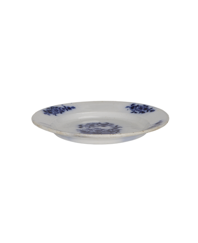 Vintage French white ceramic plate with faded blue floral pattern and rustic distress.