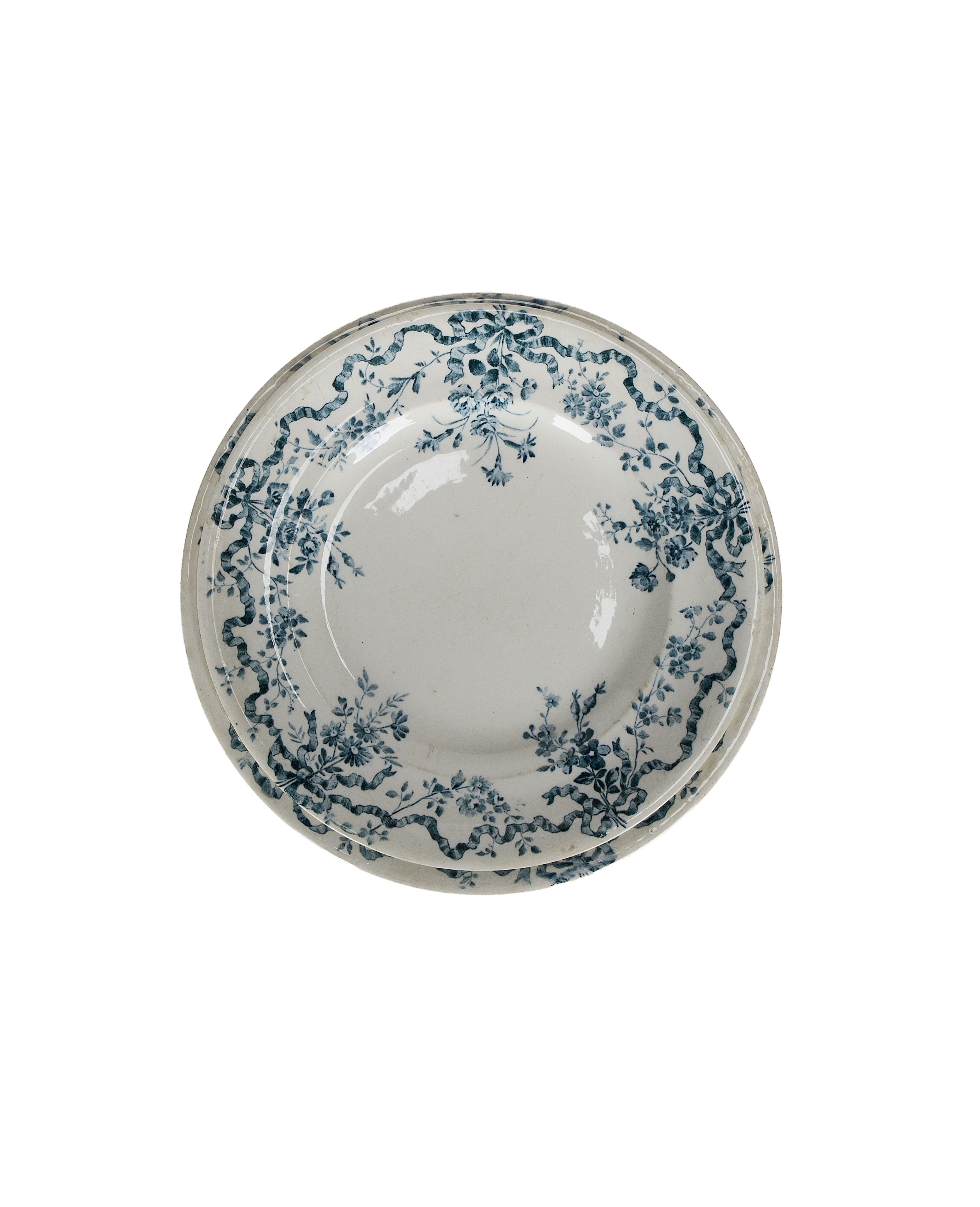 Overhead view, two vintage French porcelain wreath plates, blue ribbon floral pattern, imperfect condition.