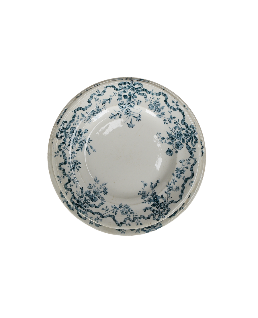Overhead view, two vintage French porcelain wreath plates, blue ribbon floral pattern, imperfect condition.