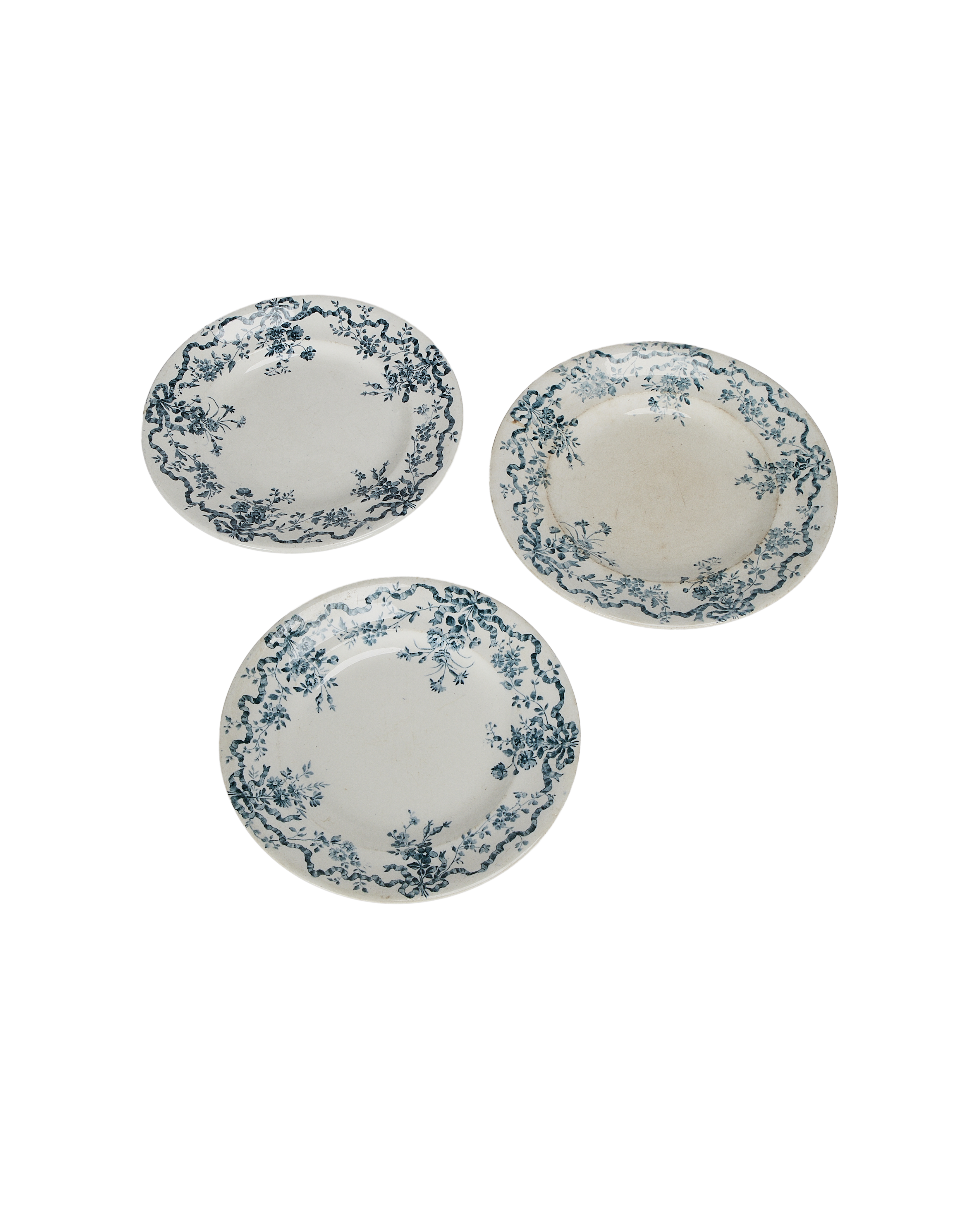 Three vintage French earthenware plates, blue floral wreath border, displaying varied wear and fading.