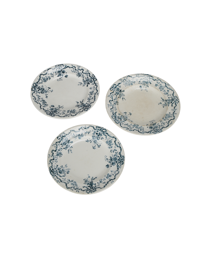 Three vintage French earthenware plates, blue floral wreath border, displaying varied wear and fading.