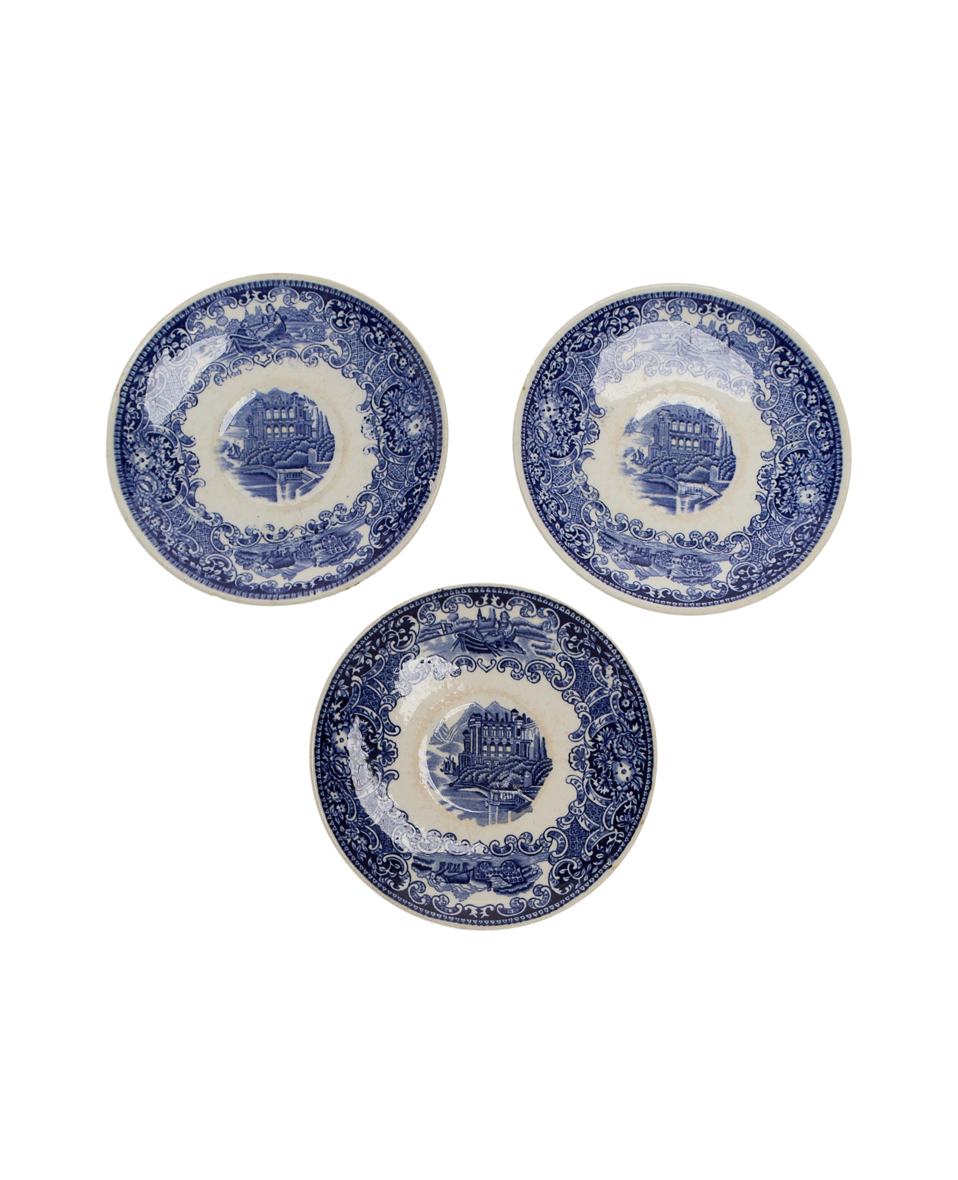 Three vintage French ceramic plates with detailed blue motif, showing crazing/character, top view.