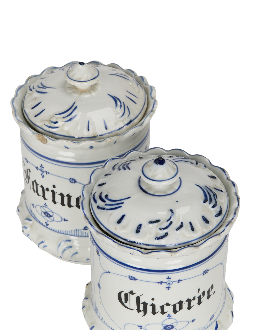 Two vintage French blue and white porcelain bulk spice jars with ornate lids.