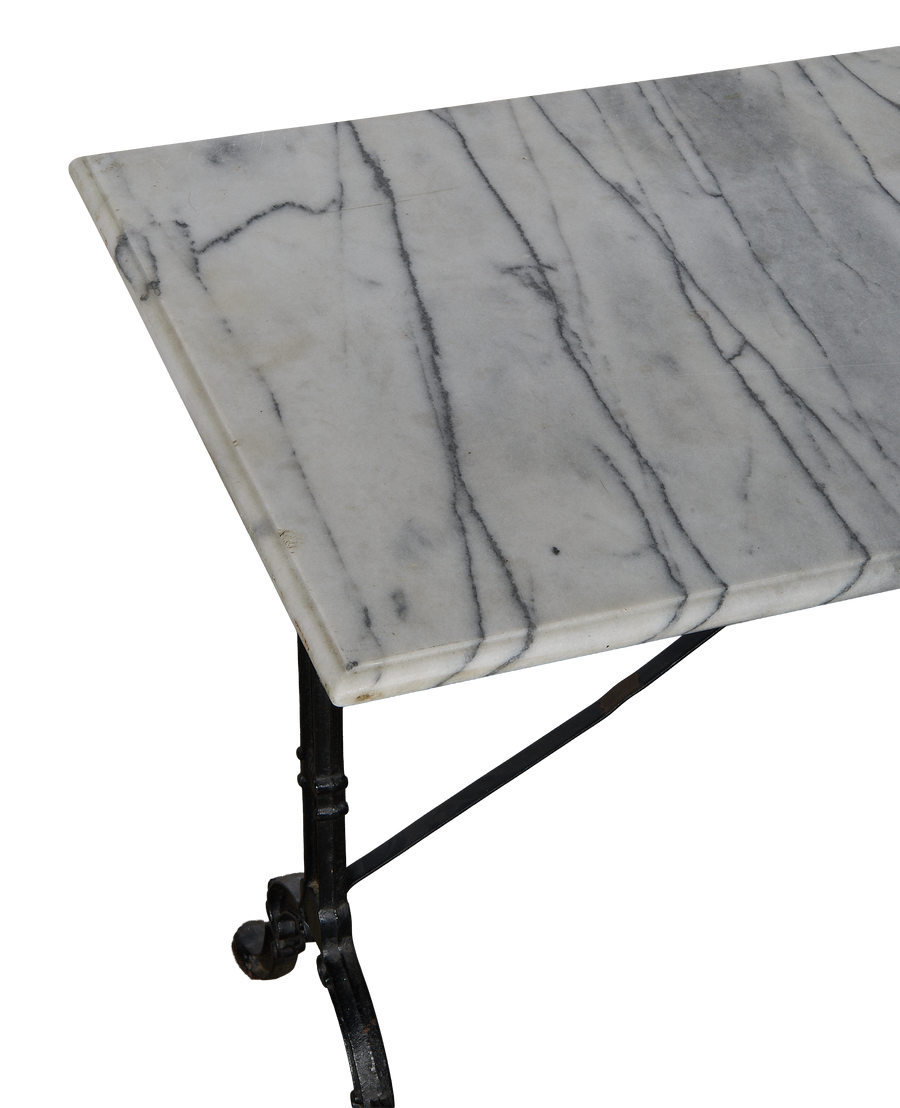 Close-up of vintage French marble bistro table's veined surface and cast iron legs.