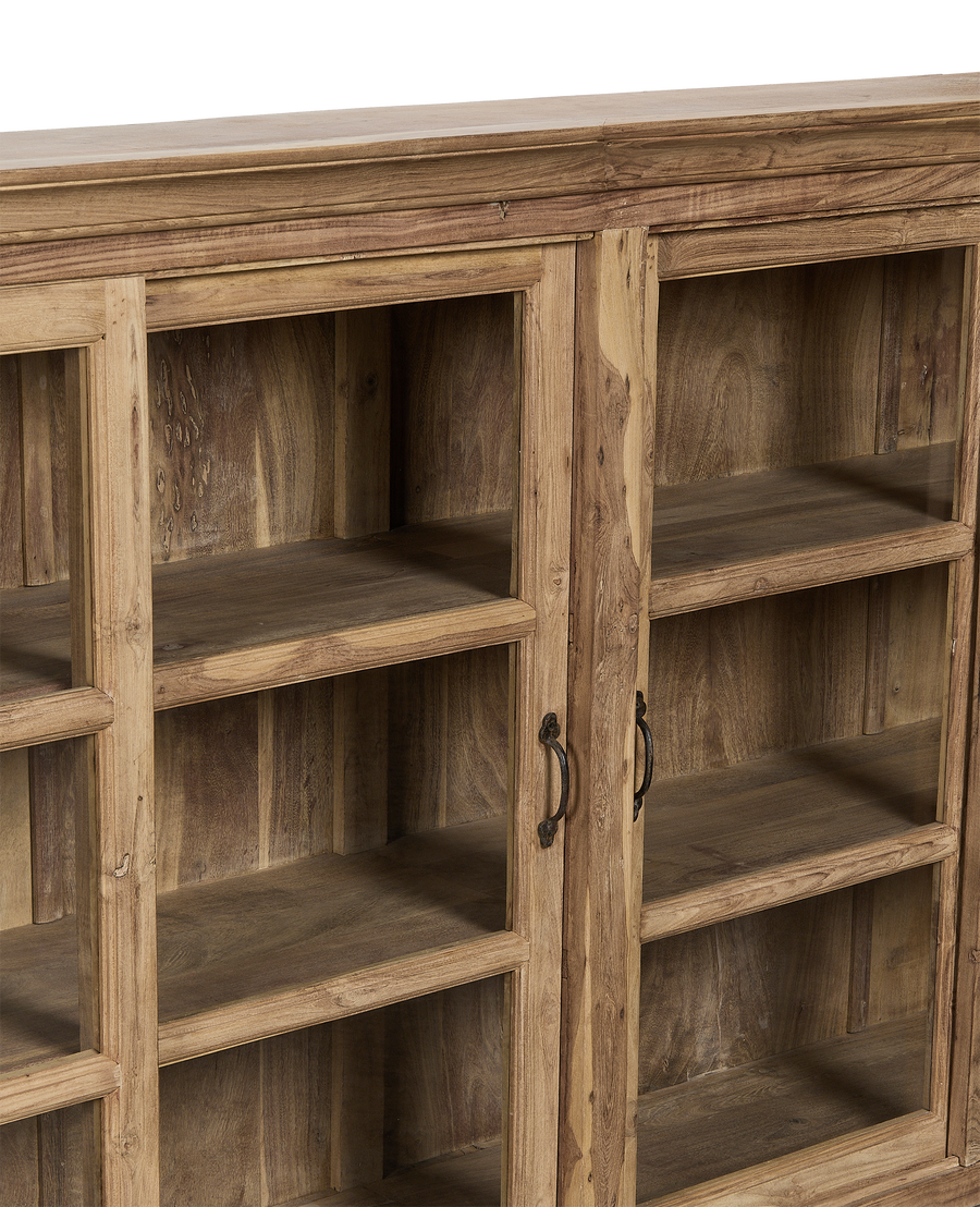 Close-up of vintage bleached oak cabinet from India, showing transparent glazed doors, ornate metal handles, and interior shelving.