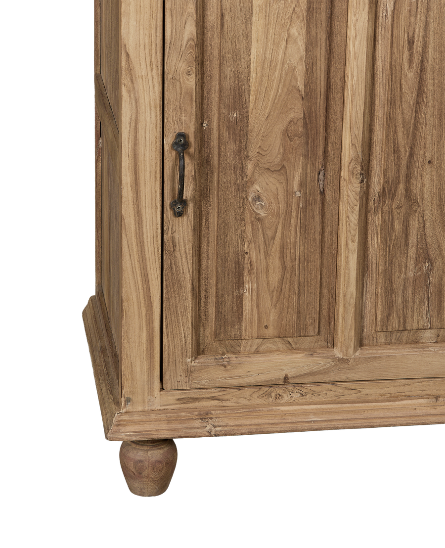 Close-up of vintage bleached oak cabinet corner, showing ornate handle and turned foot.