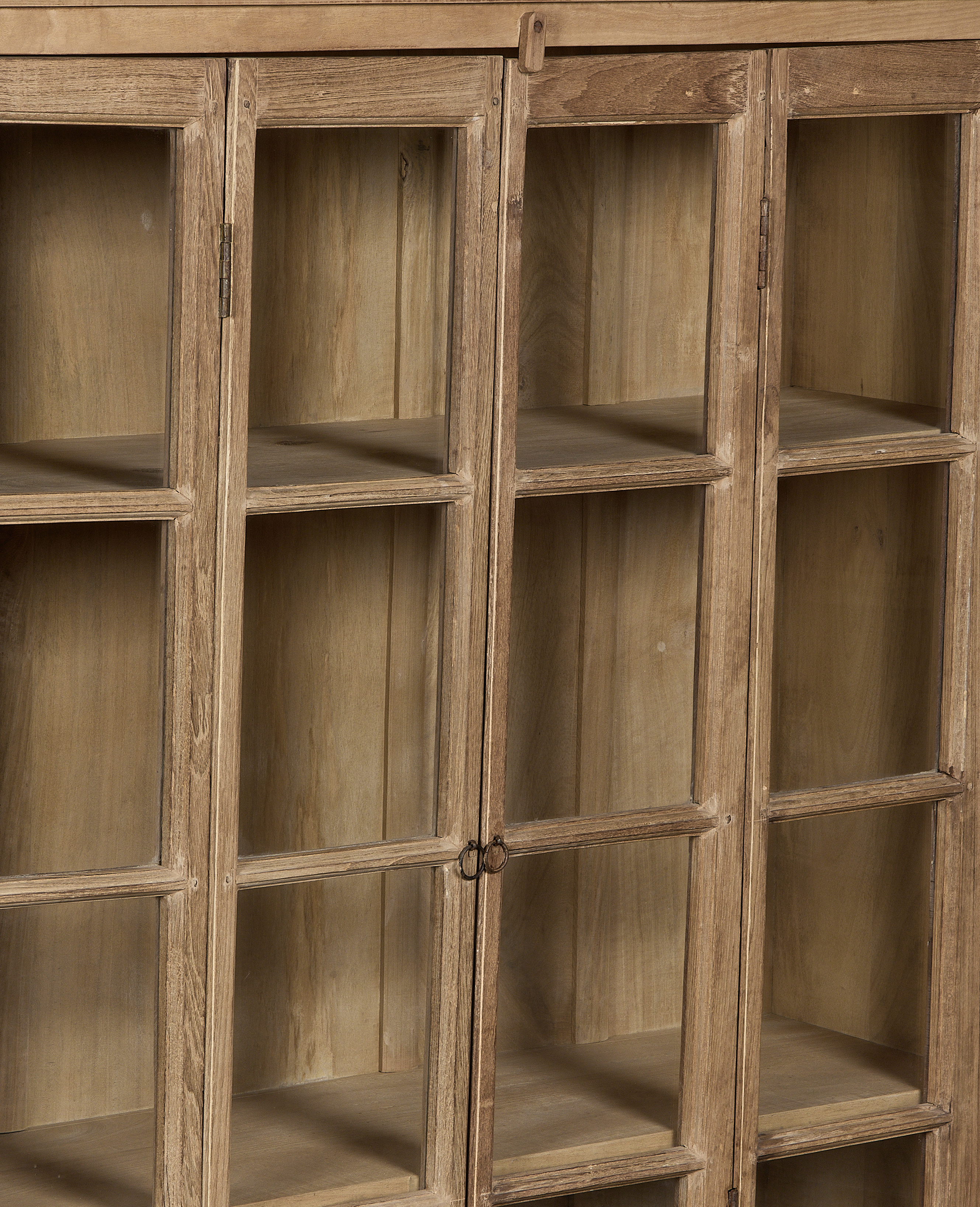 Close-up of vintage bleached oak cabinet's glass doors and visible interior shelves.