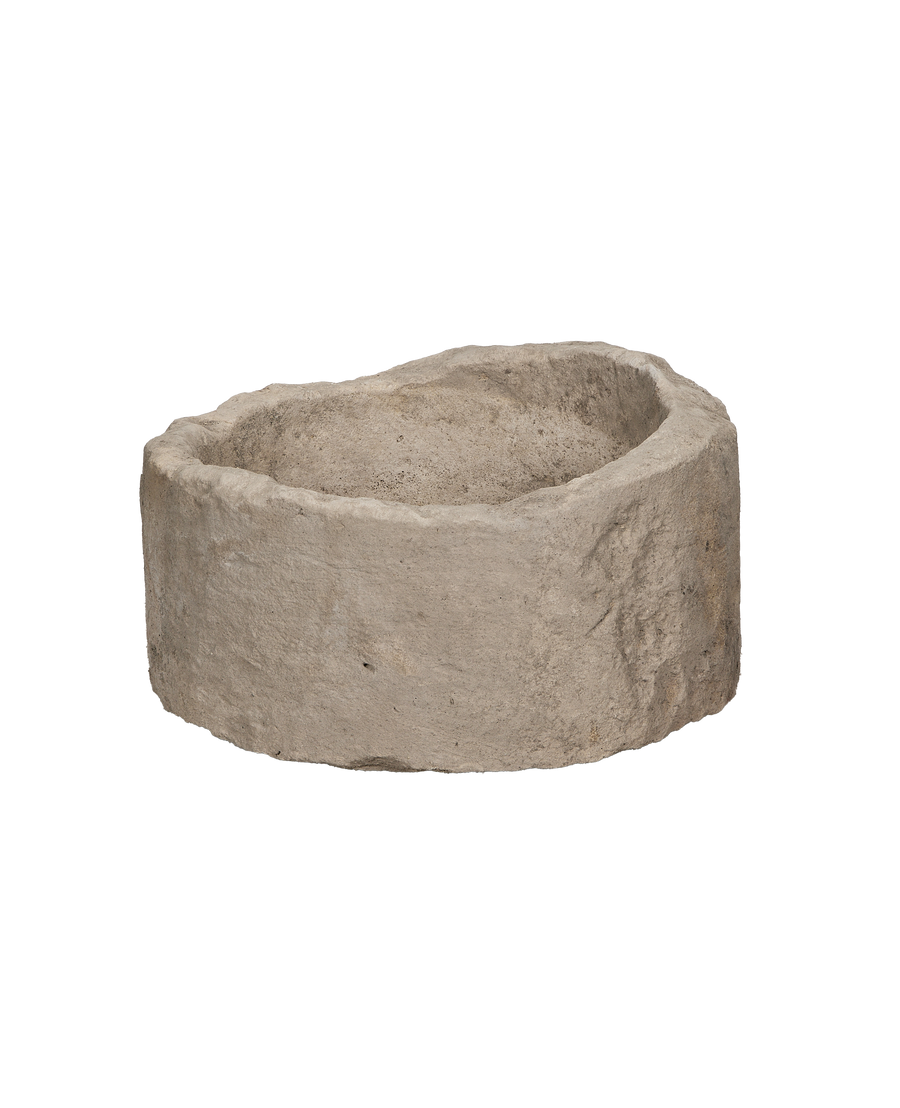 Vintage round Indonesian limestone trough, showing rough textured exterior and eroded rim from an angle.