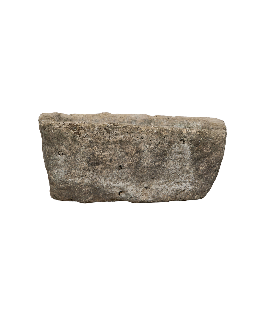 Rough-hewn vintage Indonesian limestone trough, showing weathered texture and natural imperfections, side angle.