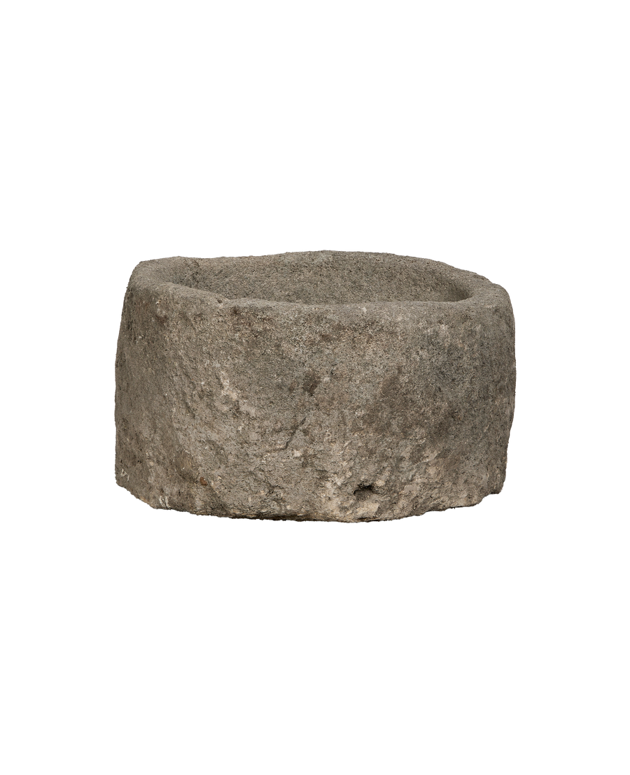 Vintage round Indonesian limestone trough, showing rough weathered exterior texture and thick walls.