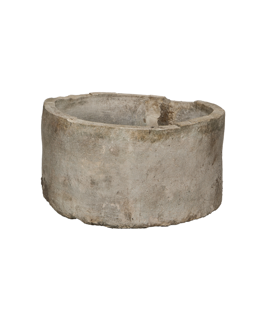 Vintage Indonesian round limestone trough, showing a complete side profile with subtle pitting and rough texture.