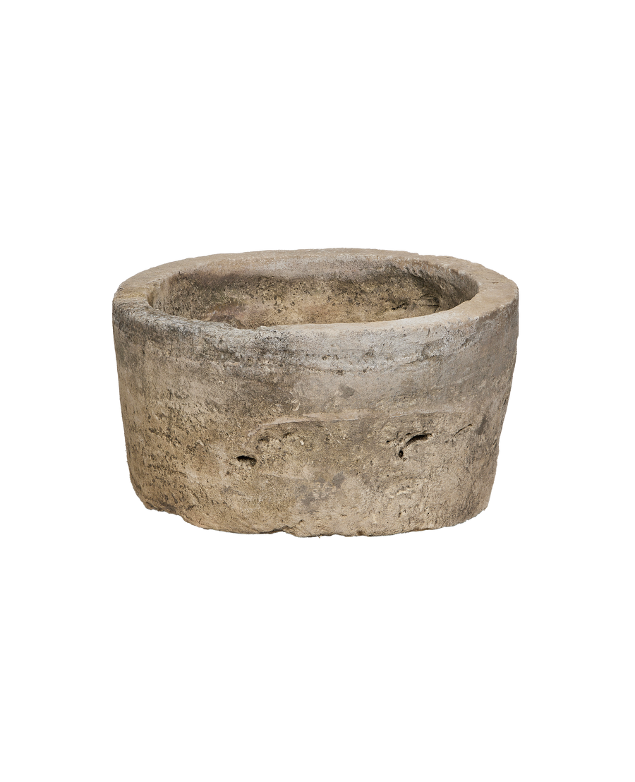 Vintage Indonesian limestone trough, partially visible, showcasing weathered texture and circular shape from a low angle.