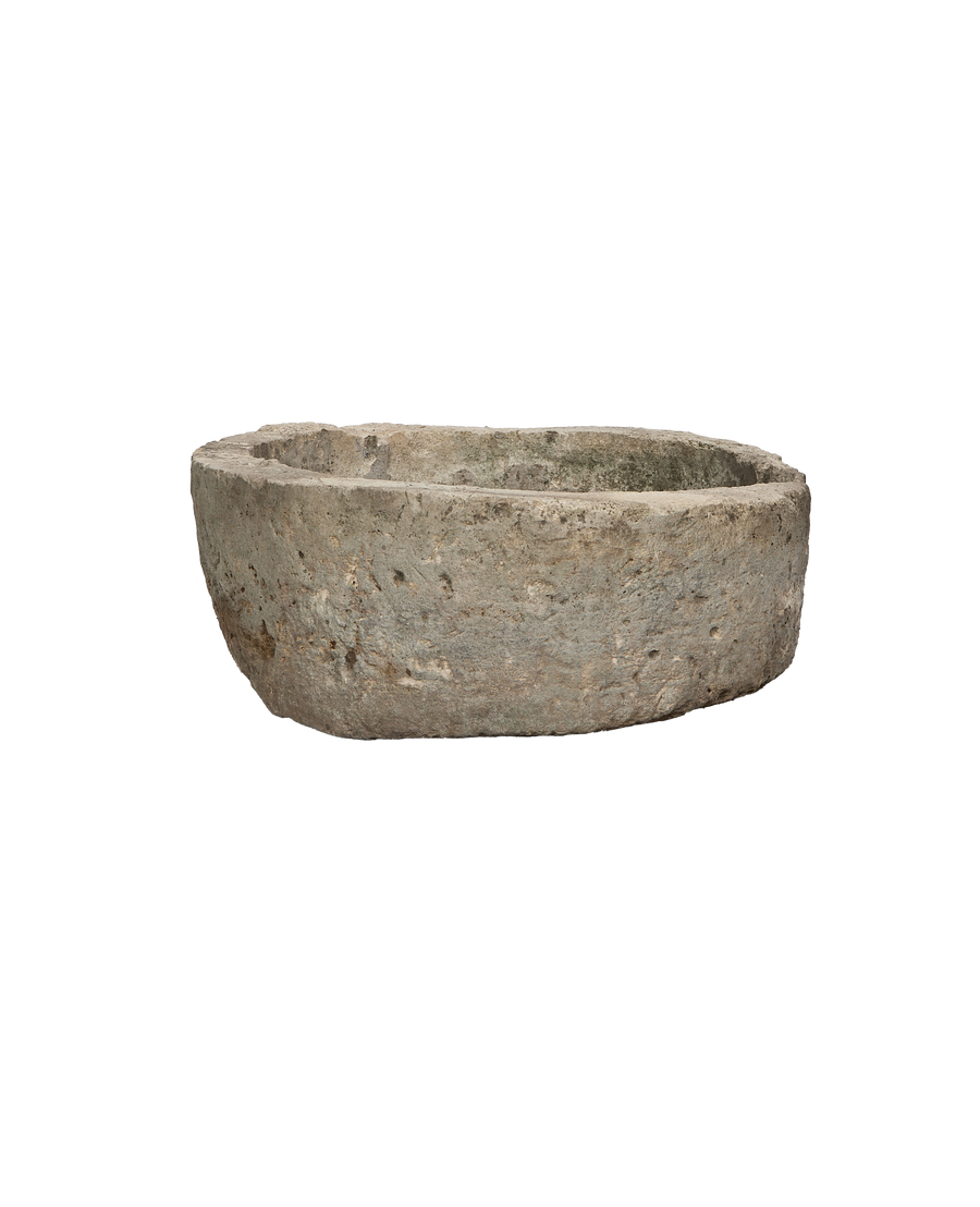 Vintage round Indonesian limestone trough, showing textured natural grey surface from a side view.