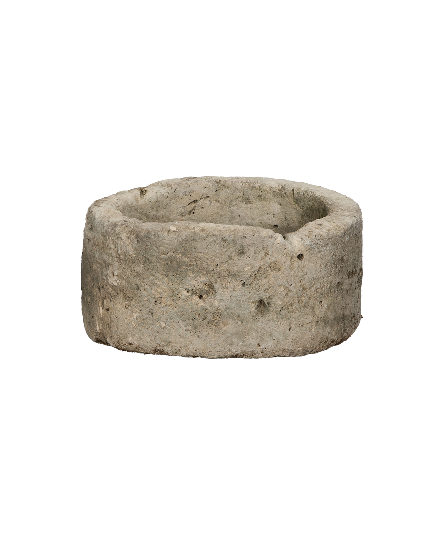Vintage round Indonesian limestone trough showing weathered texture and natural imperfections, side-angle view.