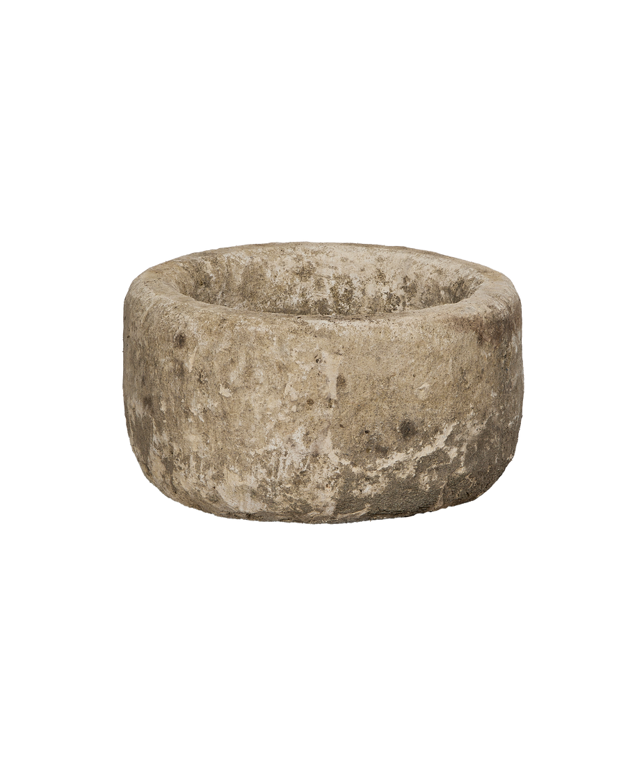 Vintage round Indonesian limestone trough from a lower angle, highlighting its weathered, uneven texture.