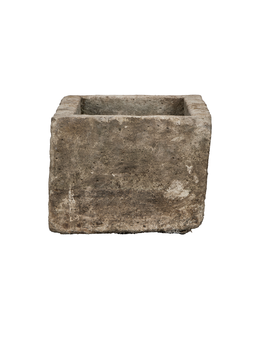 Vintage Indonesian limestone trough, square shape, showing rough, weathered stone texture from side angle.
