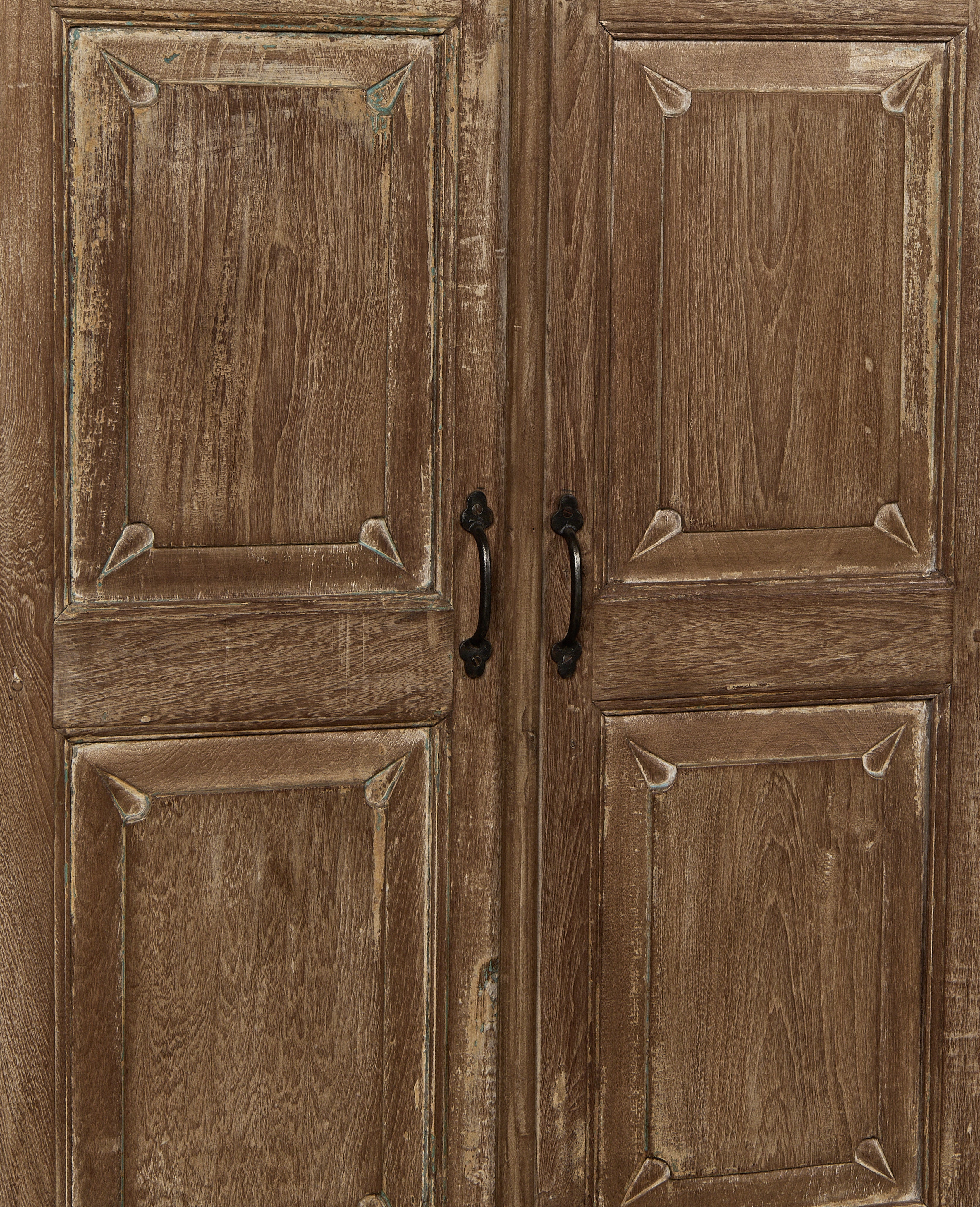Detailed view of Indian vintage oak cabinet doors with distressed natural finish and ornate black iron handles.