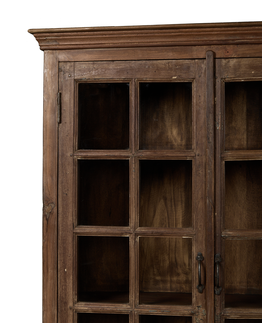 Left-side detail of vintage Indian oak wood cabinet, showcasing paneled glass doors and rustic hinge.