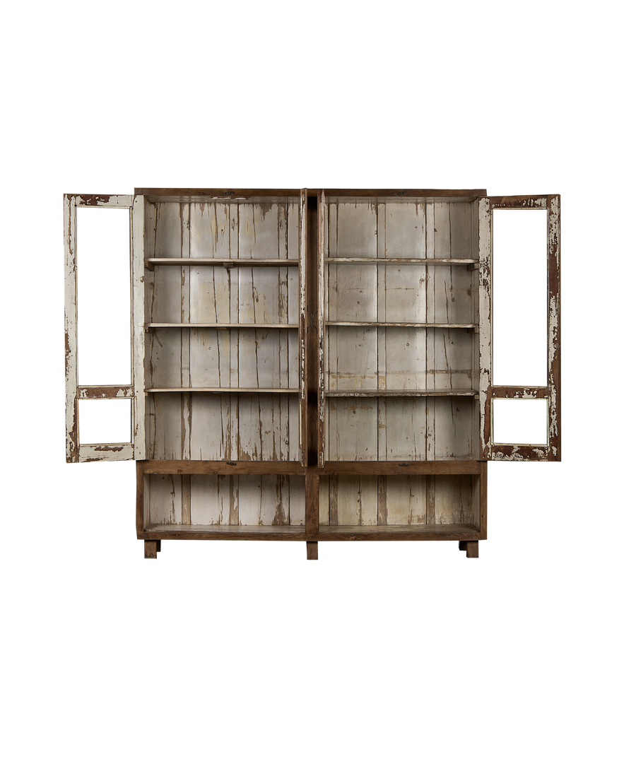 Open doors of vintage Indian oak wood cabinet revealing distressed white shelves.
