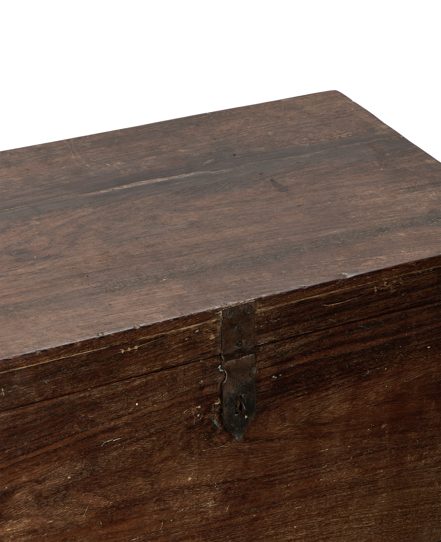 Close-up of vintage Indian oak wood chest lid with rustic metal latch.