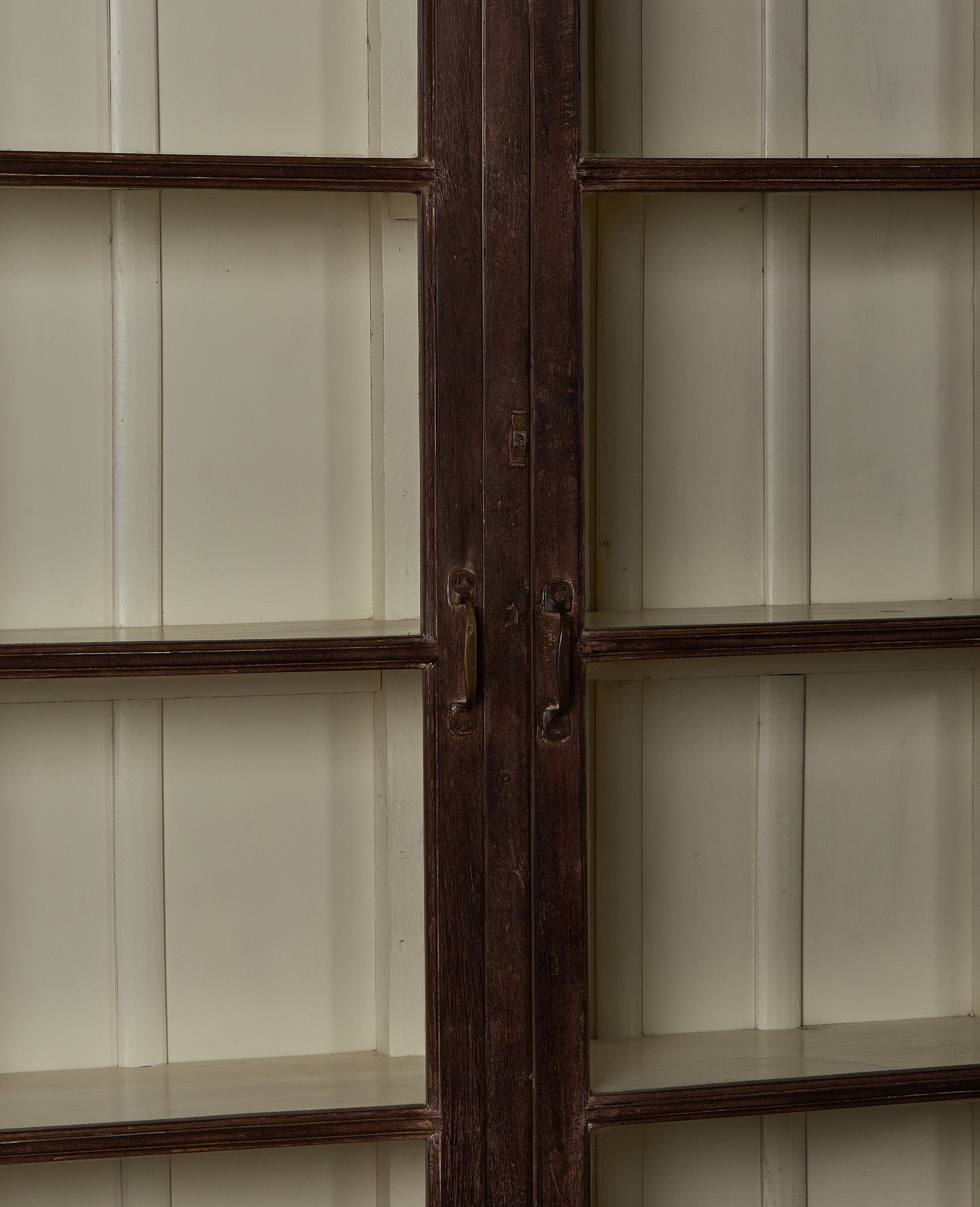Close-up of vintage Indian oak display cabinet's dark wood door frame and hardware.