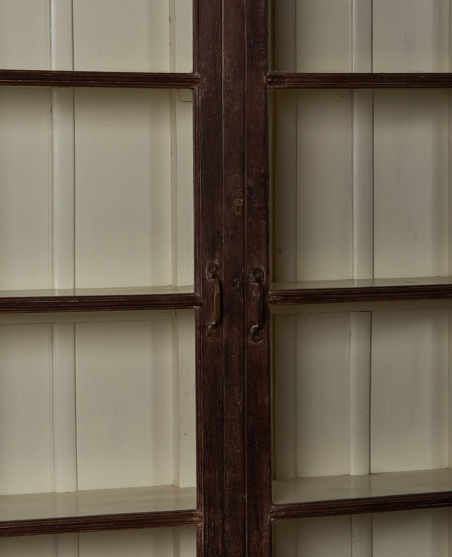 Close-up of vintage Indian oak display cabinet's dark wood door frame and hardware.