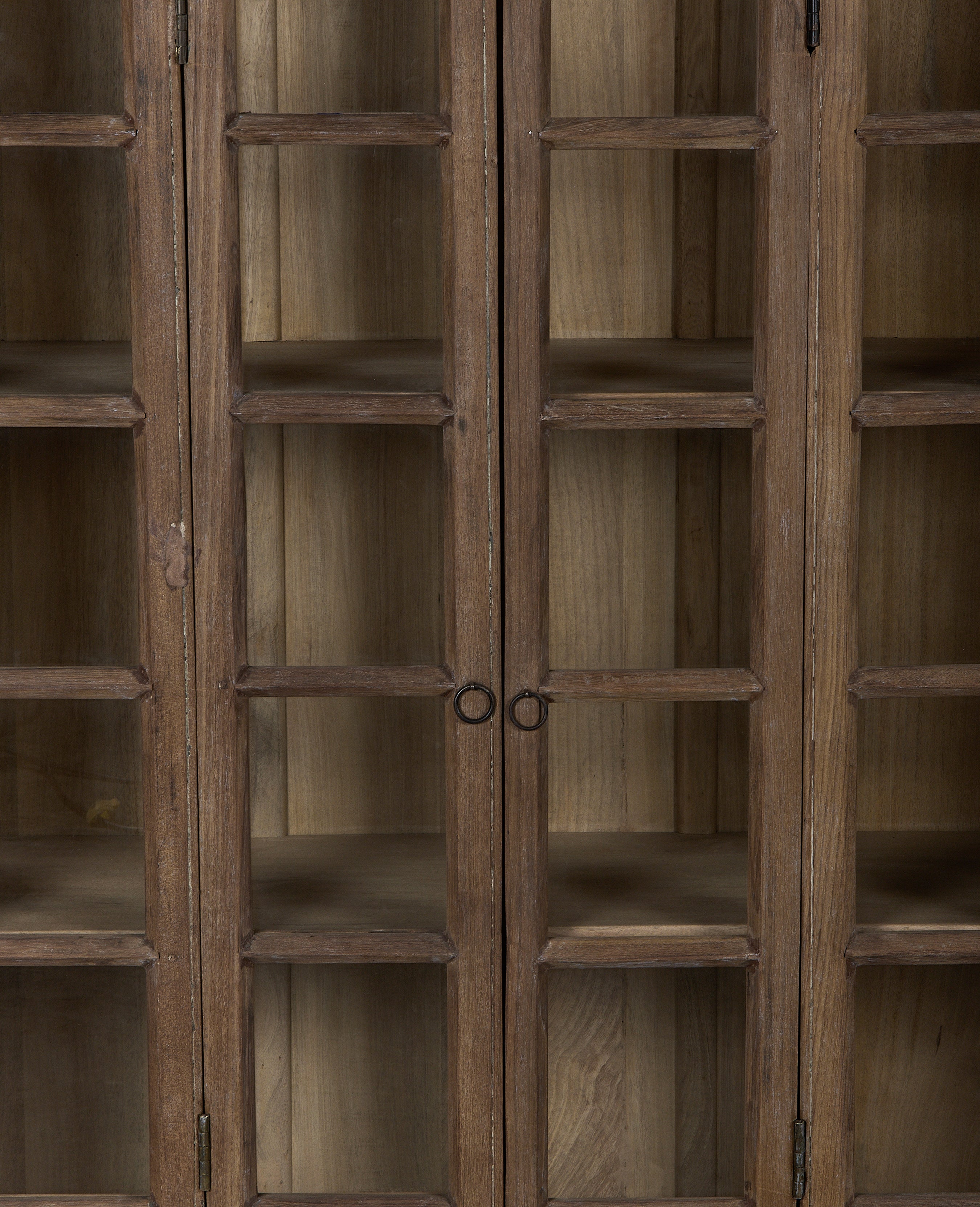 Close-up of vintage Indian bleached oak cabinet with glass panel doors and handles.