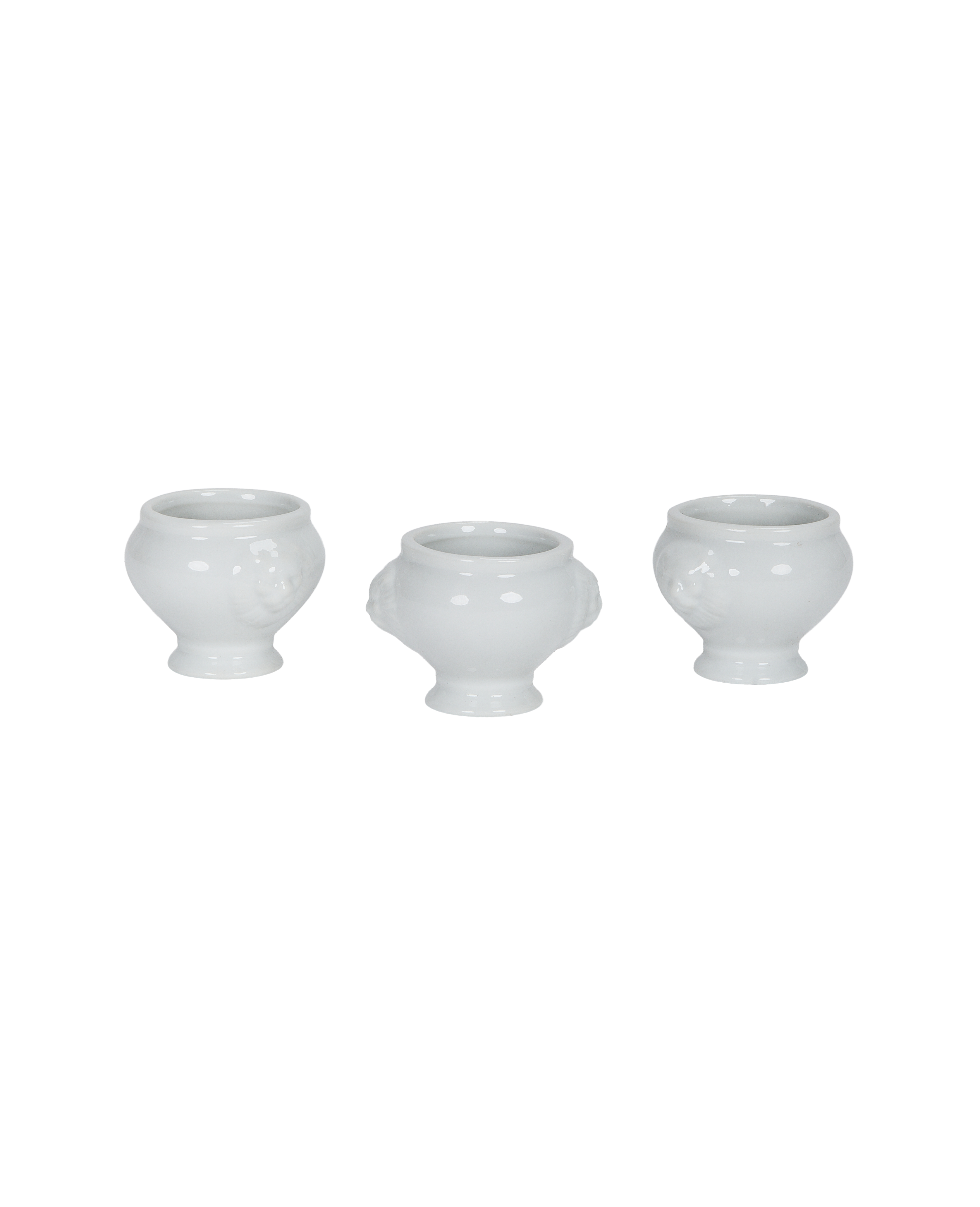 Three white vintage French lion-head salt cellars, showing side profiles and details.