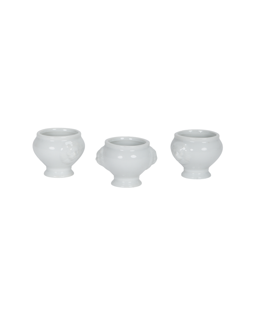 Three white vintage French lion-head salt cellars, showing side profiles and details.