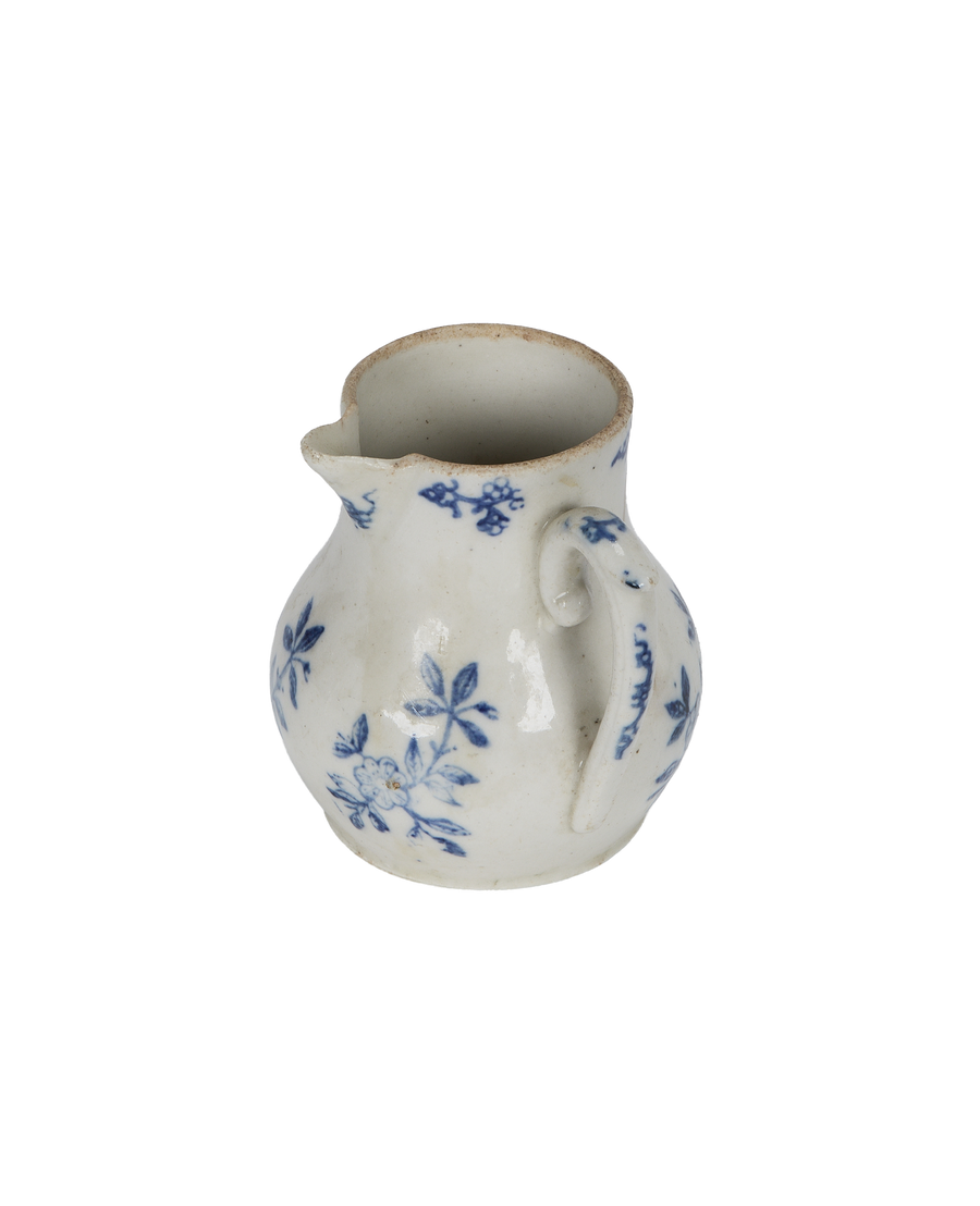 Vintage French creamer, side view showcasing handle and scattered blue floral motifs.