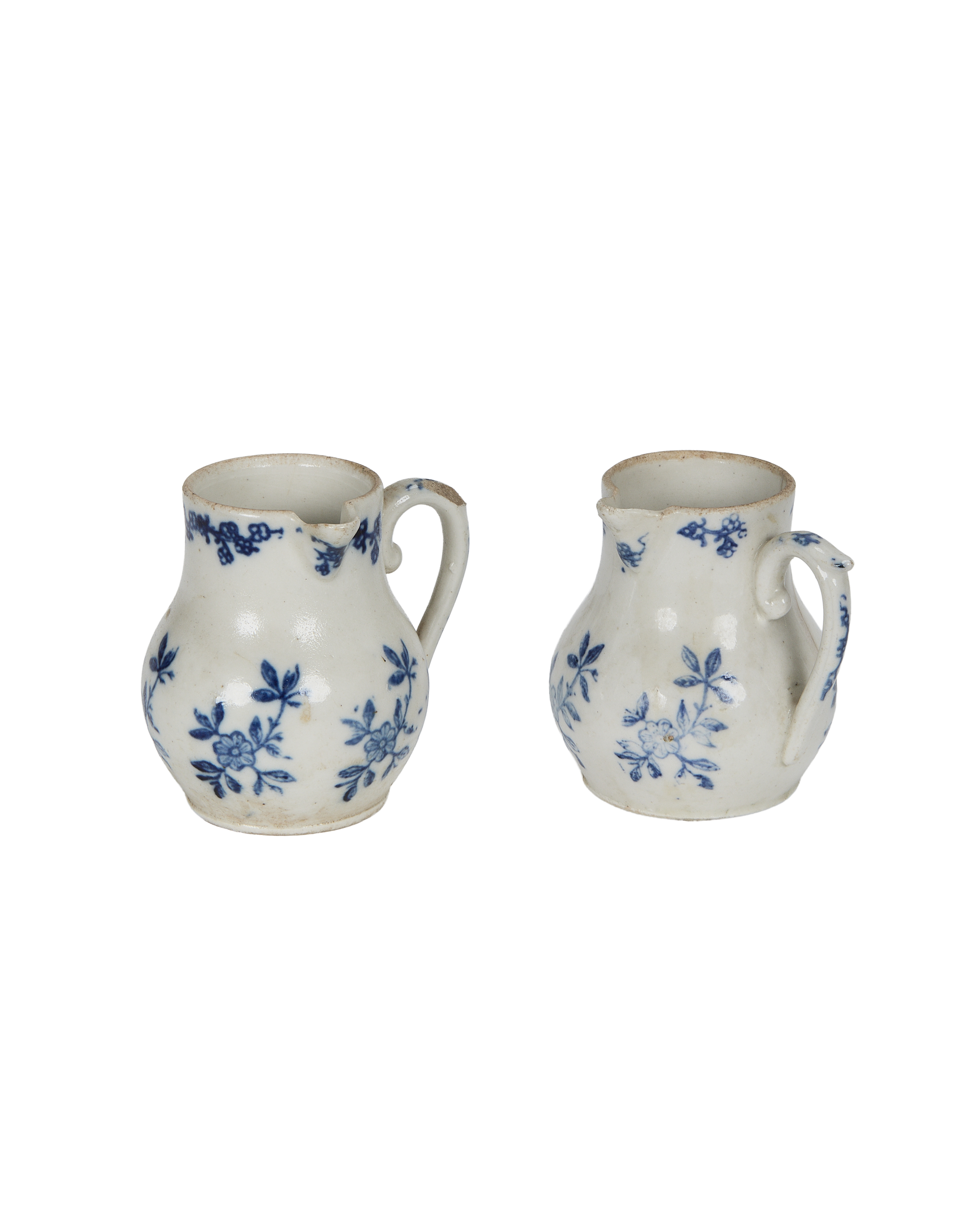 Pair of vintage French blue floral ceramic creamers, showcasing aged condition and handles.