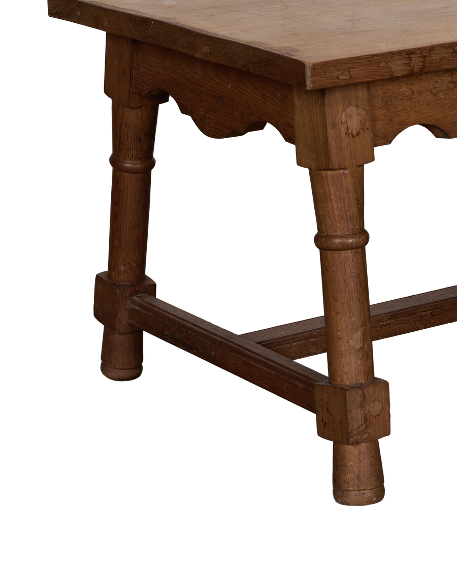 Vintage French oak coffee table showcasing detailed side frame and turned leg.