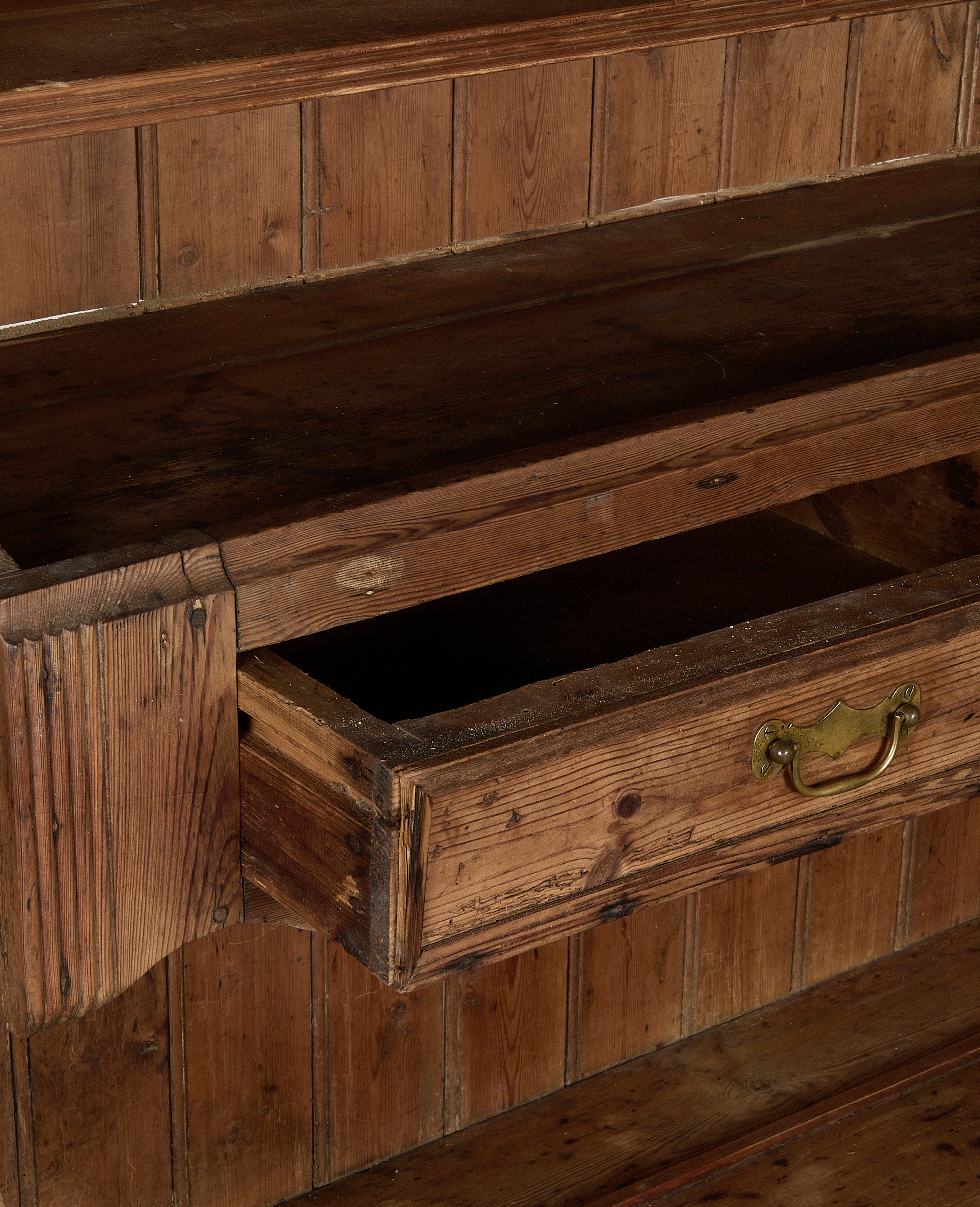 Open drawer detailed with brass handle on vintage French oak china cabinet.