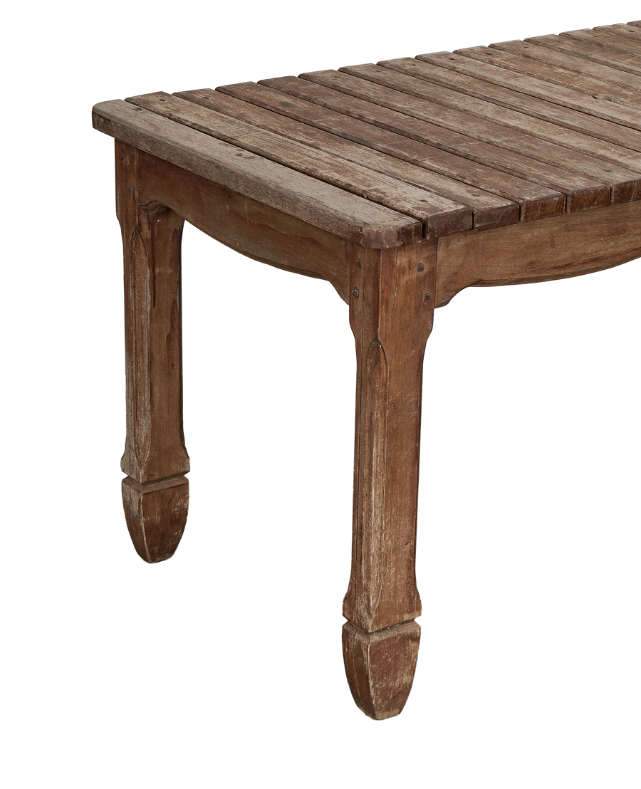 Vintage French oak patio table's slatted top and carved legs, showing distressed wood texture.
