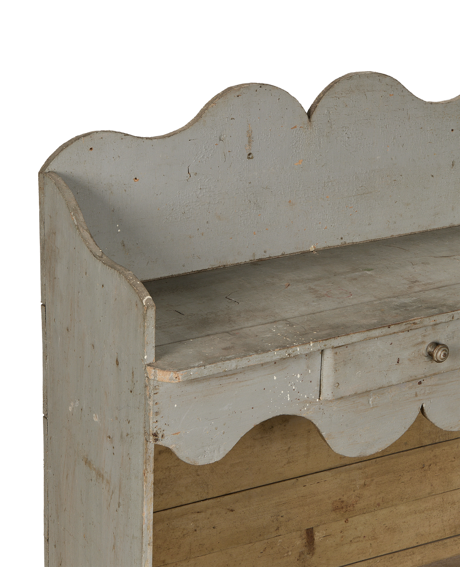 Vintage French oak scalloped shelving close-up, showing faded gray paint, drawer handle, and patina.