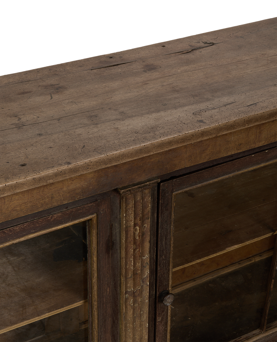 Close-up of vintage French oak sideboard top showing distressed wood surface and glass doors.