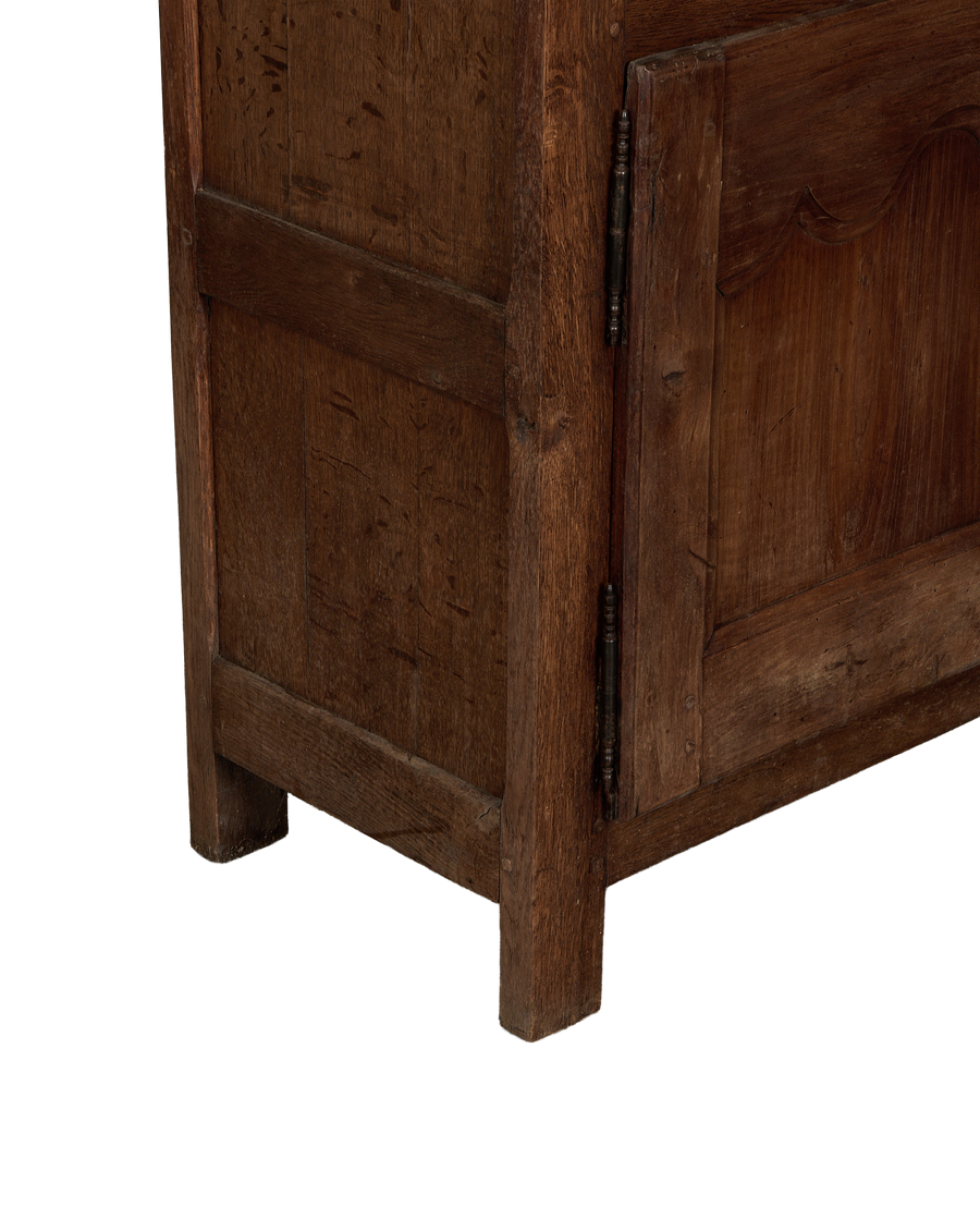 Vintage French oak cabinet detail, showing lower carved panel, aged wood texture, and rustic metal hinge.