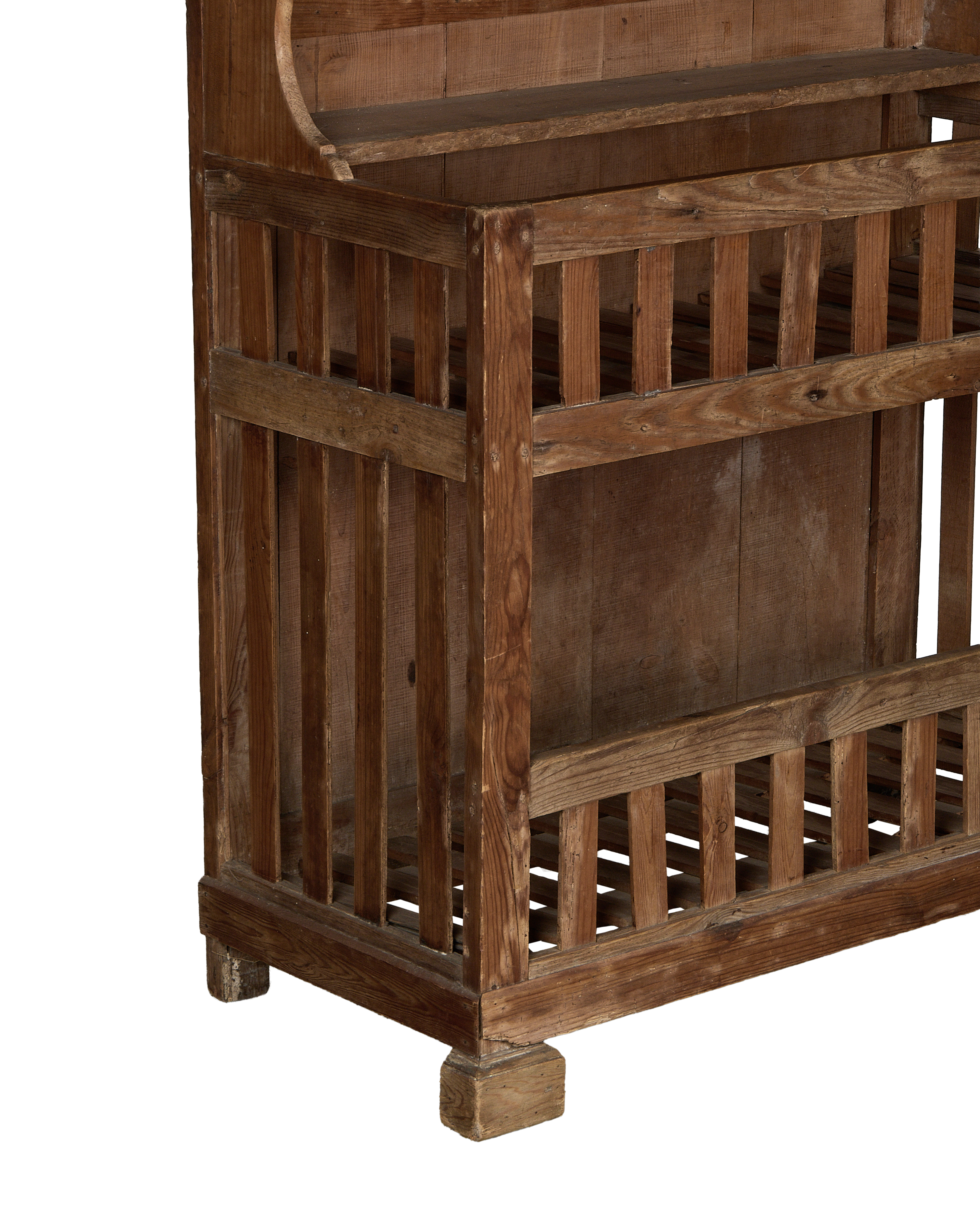 Bottom left corner of vintage French oak baker's cabinet, showing open slatted shelving.