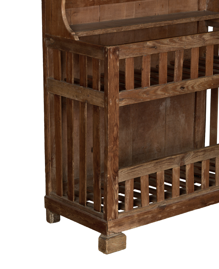 Bottom left corner of vintage French oak baker's cabinet, showing open slatted shelving.