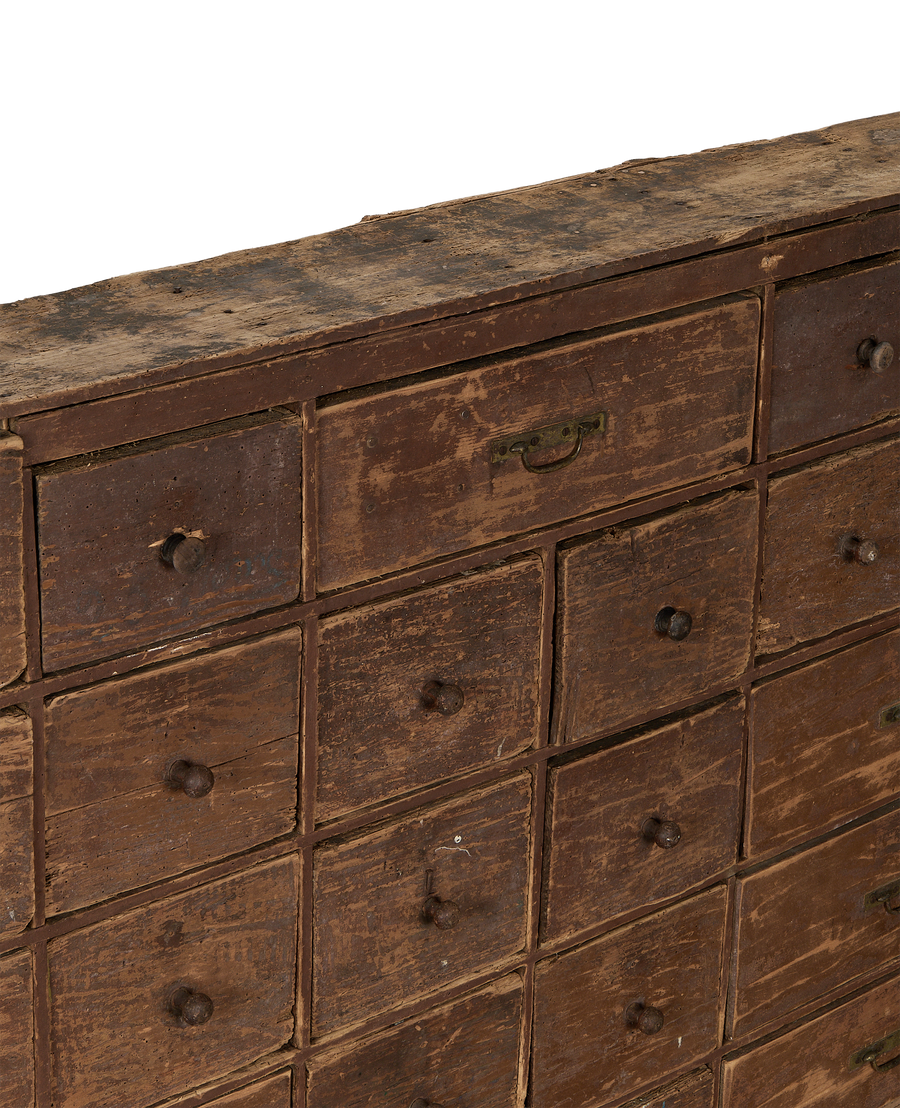 Close-up of vintage French oak apothecary sideboard drawers, revealing distressed brown finish and knobs.